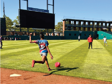 student kicking a kickball inside a baseball stadium